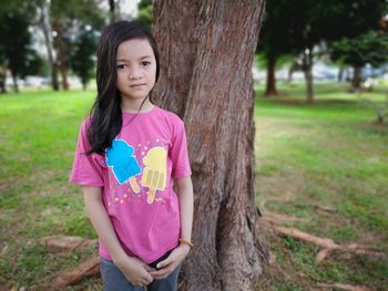 Portrait of cute girl standing against trees in park