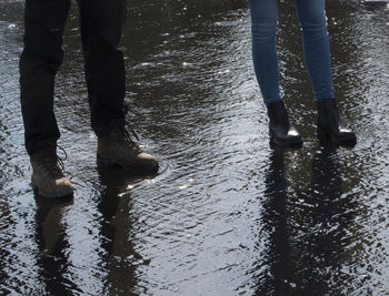 Low section of people standing on puddle during rainy season
