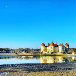 Castle moritzburg by lake against clear blue sky