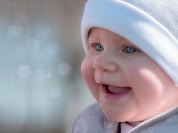 Close-up of cute baby girl with blue eyes looking away