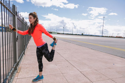 Woman stretching while standing on footpath