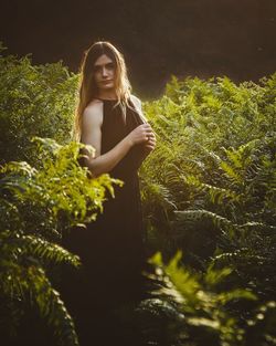 Portrait of young woman standing amidst plants