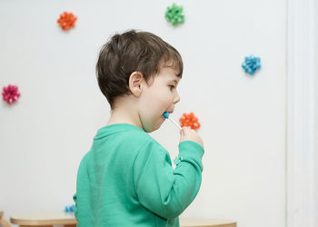 Cute baby boy enjoying a lollipop at home