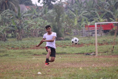 Full length of boy playing soccer on field