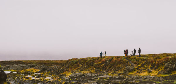 People on land against clear sky