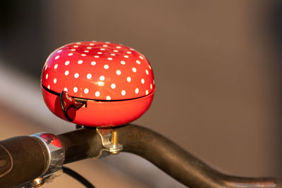 Red bike bell with white polka dots in evening sunshine and blurred background for healthy mobility