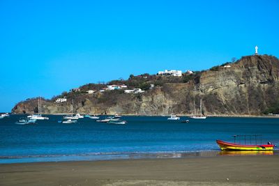 Sailboats moored at harbor against clear blue sky