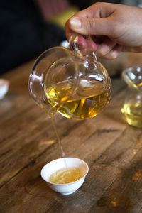 Close-up of hand pouring tea in glass