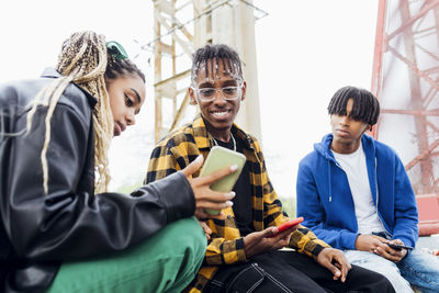 Young woman sharing smart phone with friends