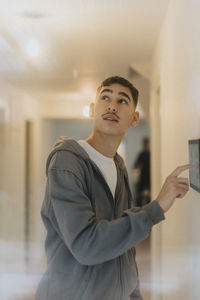 Teenage boy adjusting room lights through digital tablet while standing at smart home