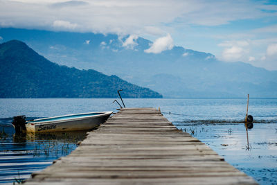 Pier over lake against cloudy sky 