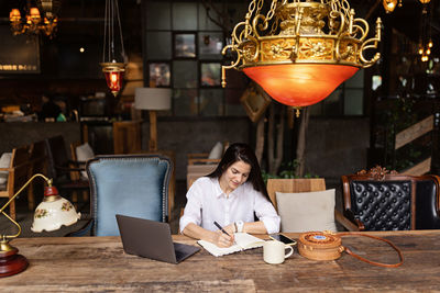 Young caucasian business woman with long brunette hair working on laptop in cafe. 