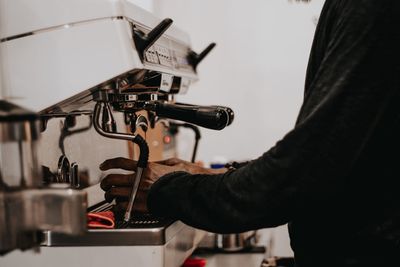 Midsection of man preparing coffee in cafe