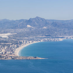 Aerial view of city by sea against sky