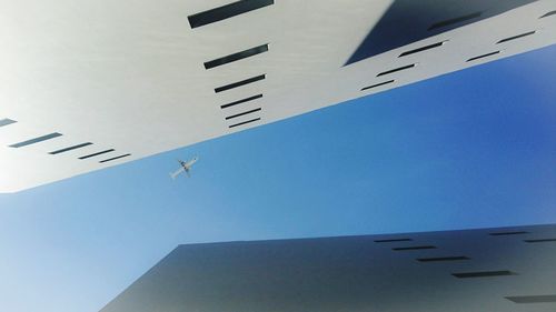 Low angle view of airplane flying against clear blue sky