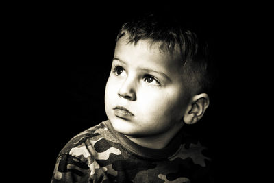 Portrait of cute boy against black background