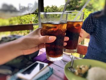 Cropped hands of friends toasting cold drinks at restaurant