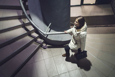 High angle view of girl sitting on tiled floor