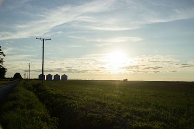 Scenic view of grassy field against sky at sunset