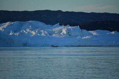 Scenic view of sea and snowcapped mountain against sky