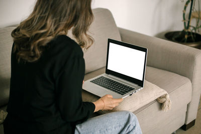 Woman using laptop on sofa at home