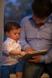 Father with son using digital tablet while sitting at home