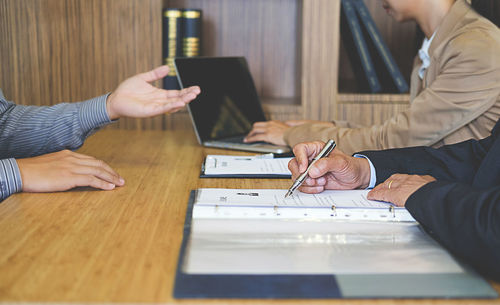 Midsection of business people with candidate at desk during interview