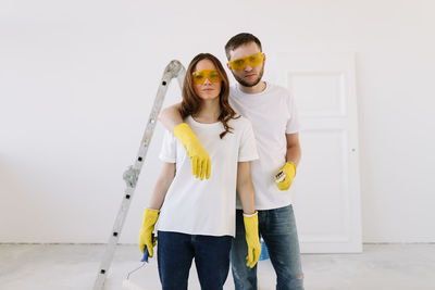 A young couple in love have moved into a new house and are making repairs painting white walls