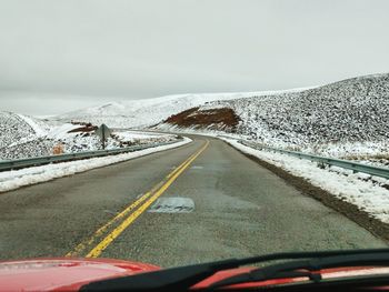 Snow covered mountains against sky seen through car windshield