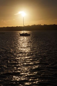 Silhouette of boat sailing in sea during sunset