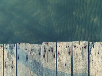 Close-up of wooden fence on pier against lake