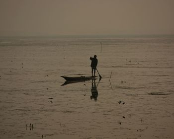 Silhouette man standing on beach against sky