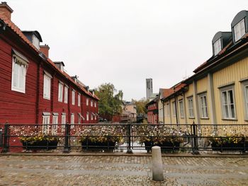 Houses by street in city against sky
