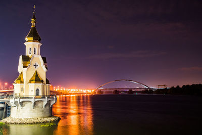 View of illuminated arch bridge and building against sky at night