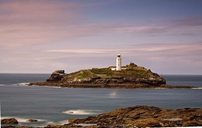 Lighthouse by sea against sky