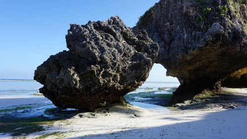Rock formation on beach against clear blue sky