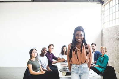 Portrait of cheerful businesswoman working with computer programmers in board room