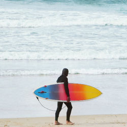 Rear view of man with surfboard on beach