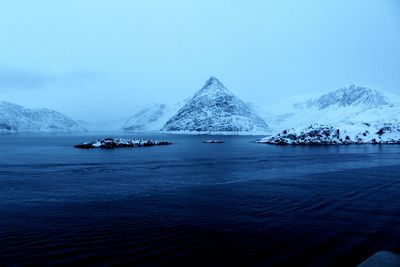 Scenic view of sea by snowcapped mountain against sky