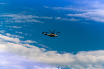 Low angle view of helicopter flying against blue sky