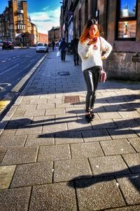 Full length portrait of woman in city against sky