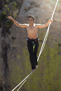 Full length of shirtless man walking on rope