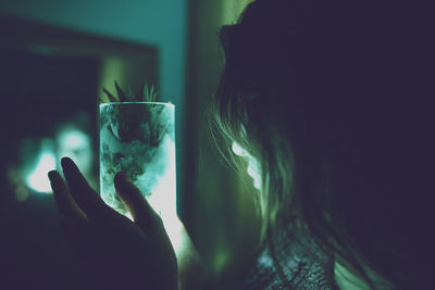 Close-up of woman holding pineapple drink in illuminated container