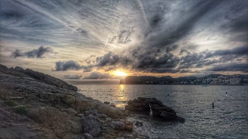 Scenic view of sea against dramatic sky during sunset