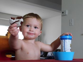 Boy having food while sitting on chair at home