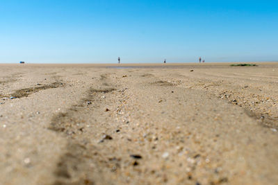 Surface level of sandy beach against clear blue sky