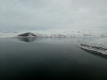 Scenic view of lake by snowcapped mountain against sky