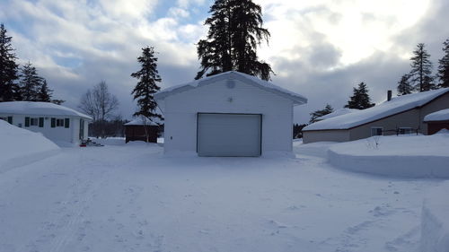 Snow covered houses against cloudy sky