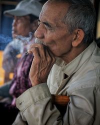Close-up of senior smoking cigarette by man