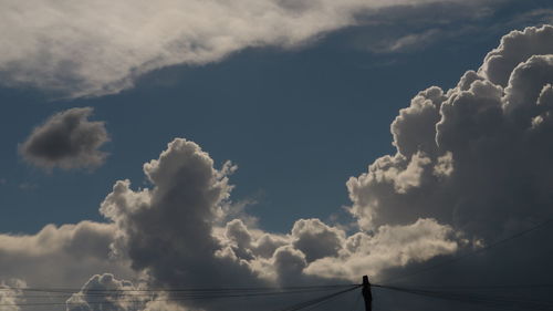 Low angle view of power lines against cloudy sky